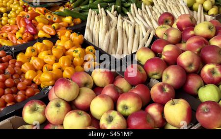 Ein Gemüsestand auf dem Straßenmarkt in Lieden mit Obst und Gemüse, einschließlich Äpfeln, gelber Paprika und weißem Spargel Stockfoto
