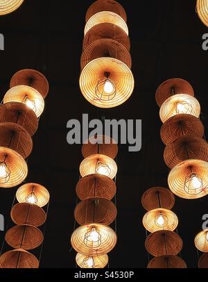 Blick auf mehrere Reihen von Hängeleuchten mit Strohhut, die von der Decke hängen, aus niedrigem Winkel. Stockfoto