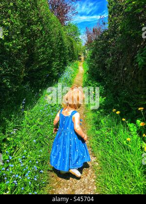 Ein kleines Mädchen, das ihr Dorf erkundet, umgeben von Farbe und Wildblumen Stockfoto