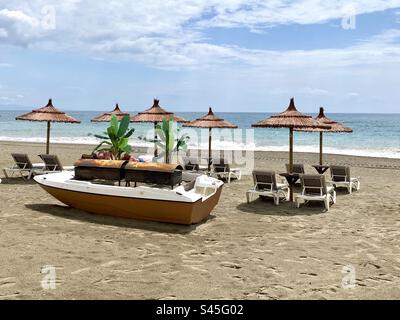 Der wunderschöne Strand bei Sabinillas in Südspanien mit Sonnenschirmen und Sonnenliegen und grillbereit Stockfoto