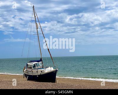 Segelboot, das am Strand gestrandet ist, nachdem es seine Anlegestelle verloren hat. Stockfoto