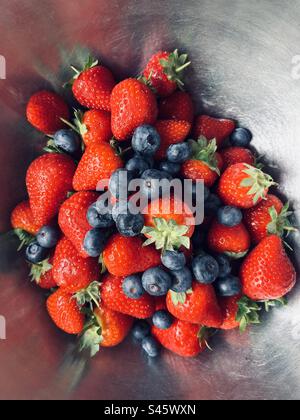 Frische Sommer-Heidelbeeren und Erdbeeren in einer Edelstahlschüssel. Stockfoto