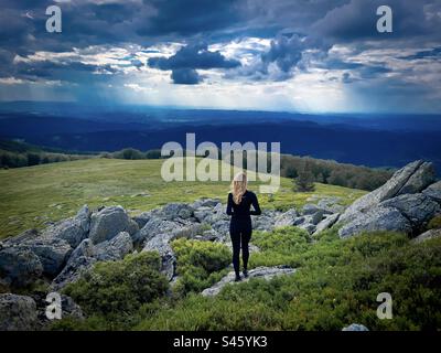 Rückansicht einer fitten Wanderin mit Blick auf die Berge an einem kalten und bewölkten Sommertag Stockfoto