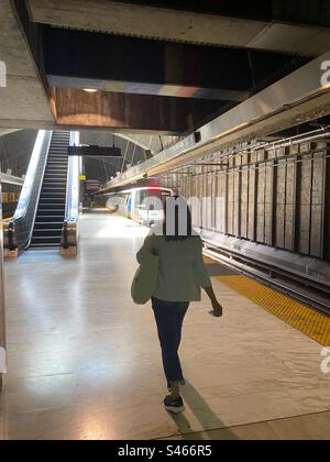 Unbekannte Frau auf dem Bahnsteig der Glen Park BART-Station in San Francisco, während der Zug aus der Station fährt Stockfoto