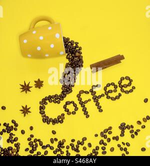 Ein gelber Becher mit Punktmuster verrät das Wort „Kaffee“ in Kaffeebohnen Stockfoto