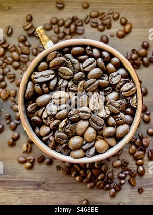 Ein Kupferbecher, von oben gesehen, gefüllt mit Kaffeebohnen Stockfoto