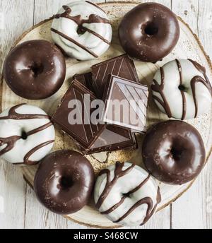 Dunkle und weiße Schokoladentoughnuts mit Schokoladenstücken auf einer Holzplatte Stockfoto