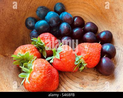 Fünf Erdbeeren, Blaubeeren und Kirschen in einer genarbten Holzschüssel. Frisch, bunt, saftig, süß, nahrhaft, Sommerfrucht. Stockfoto