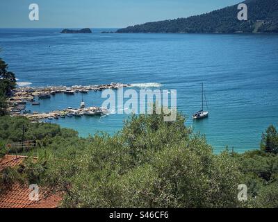 Pier mit Marmorblöcken und kleinen Booten in einer Bucht hinter Golden Beach auf der Insel Thassos, Griechenland. Stockfoto