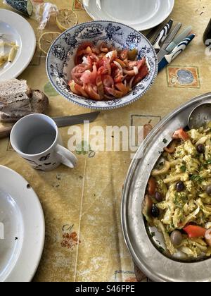 Portugiesisches Gericht „bacalhau à Brás“ (typische Mahlzeit) und Tomatensalat auf dem Tisch. Mit Besteck und Geschirr. Stockfoto