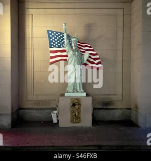 LOS ANGELES, CA, DEC 2022: Skulptur der Freiheitsstatue auf einem gebrochenen Sockel mit Sternen und Streifen-Flagge, die an der Wand dahinter in Downtown gemalt ist Stockfoto