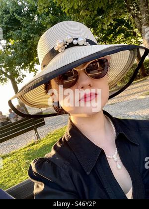 Elegante Dame mit Hut und Sonnenbrille bei Sonnenuntergang Stockfoto