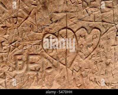 Graffiti von verbundenen Herzen, die im roten Sandstein von Kinver in Staffordshire zerkratzt sind Stockfoto