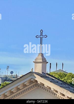 Die Dachlinie und das Kreuz auf der Basilika San Clemente im Celio-Viertel von Rom. Stockfoto