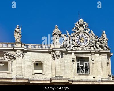 Die kunstvolle Uhr oben rechts vom Petersdom mit den Statuen der Heiligen, Vatikanstadt. Stockfoto