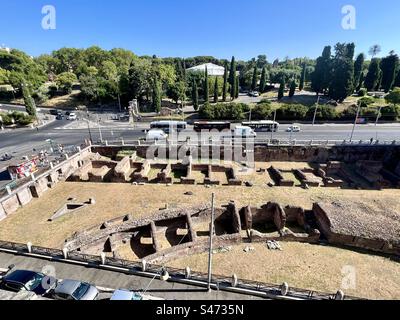 Ruinen von Ludas Magnus, einer alten Gladiatorentrainingsanlage, mit den umliegenden Straßen und dem Parco del Colle Oppio im Hintergrund. Stockfoto