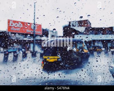 Eine automatische Rikscha im Regen aus einem Autofenster voller Wassertropfen Stockfoto