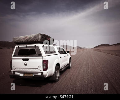 Ein weißer Geländewagen mit einem Dachzelt auf einer unbefestigten Straße in Namibia Stockfoto