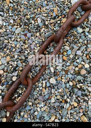 Eine große rostige Kette, die auf Schindel liegt Stockfoto