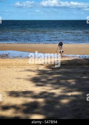 Ein Mann benutzt bei Ebbe einen Metalldetektor am Strand Stockfoto