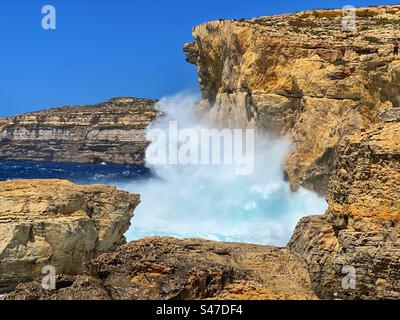 Sprühen Sie von einer großen Welle, die auf Felsen an der Küste von Gozo auf Malta trifft Stockfoto