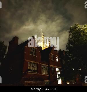 Der Victoria Tower of the Houses of Parliament, der nachts vom Gelände der Westminster Abbey aus mit einer Flagge beleuchtet wurde Stockfoto