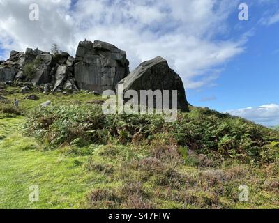 Blick auf die, Cow und Calf Rock, mit Figuren auf dem großen Felsen, an einem bewölkten Tag in Ilkley, Yorkshire, Großbritannien Stockfoto