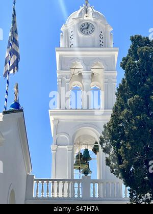 Vor dem Glockenturm von Panagia Ton Eisodion, der Himmelfahrtskirche Marias, auf dem Hauptplatz von Megalochori, Santorin, fällt ein Sonnenstrahl. Stockfoto