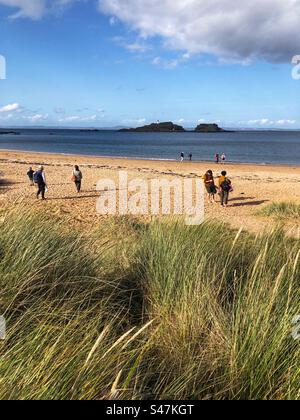 Menschen am Yellowcraig Beach, mit Blick auf den Leuchtturm Fidra, East Lothian Coast, Schottland Stockfoto