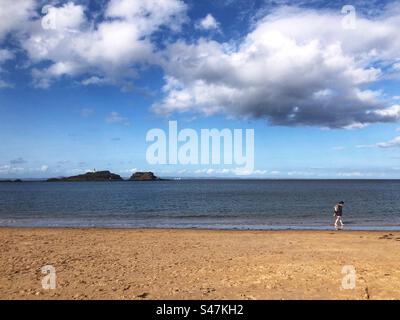 Solitary Walker am Yellowcraig Beach, mit Blick auf den Leuchtturm Fidra, East Lothian Coast, Schottland Stockfoto