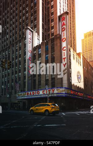 Städtische Skyline der Radio City Music Hall in New York City bei Sonnenuntergang mit gelbem Taxi und Kopierraum Stockfoto