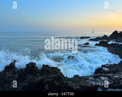 Wellen plätschern in der Abenddämmerung auf Felsen, Pwll du, Gower, Swansea, Südwestwales. Oktober. Stockfoto