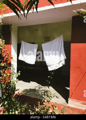 Zwei weiße Handtücher hängen an einer Wäscheleine und trocknen in der Sonne Stockfoto