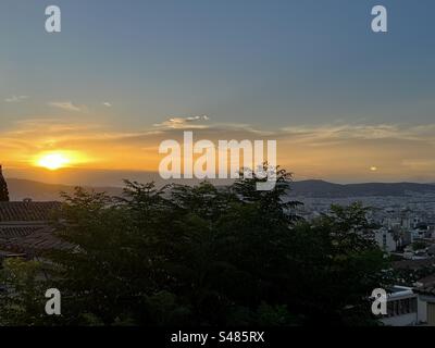 Lebhafte orange-gelbe Sonne untergeht an einem Sommerabend in Athen Stockfoto