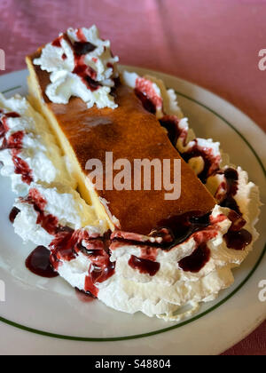 Käsekuchen mit Sahne und Himbeersirup. Stockfoto