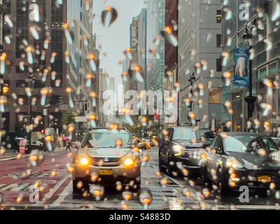 Regnerischer Tag in New York City mit Scheinwerfern aus dem Auto, die sich in Regentropfen auf das Autofenster spiegeln Stockfoto