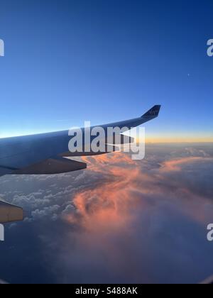 Blick aus einem Flugzeugfenster im Flug, mit Blick auf den Flügel und den Sonnenuntergang Stockfoto