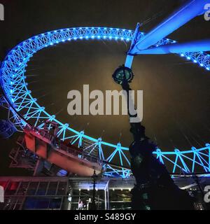 Aus nächster Nähe sehen Sie Londons Millennium Wheel oder das „Auge“ bei Nacht mit einer traditionellen Lampe vom Südufer der Themse - blaue Perspektive Stockfoto