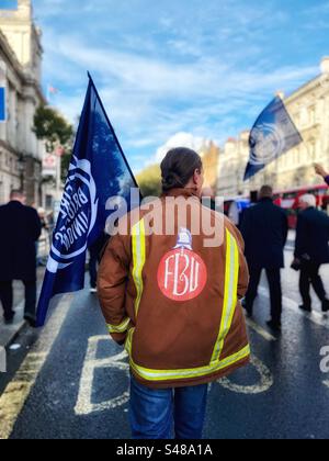 Ein Feuerwehrmann mit FBU-Logo-Jacke - auf einer Demonstration in Westminster, London am 1. November 2023 hält Flagge. Die FBU ist eine gewerkschaft, die Arbeiter der Feuerwehr im ganzen Vereinigten Königreich vertritt Stockfoto