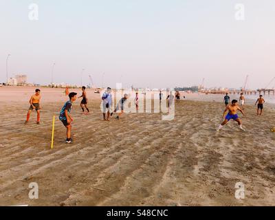 Junge Männer spielen Fußball am Strand Stockfoto