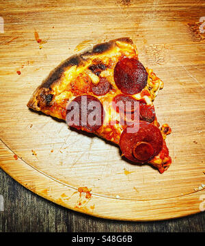Foto-visuelle Draufsicht auf ein dreieckiges leckeres Stück Pizza, das gerade von oben auf einem Holzteller gebacken wird Stockfoto