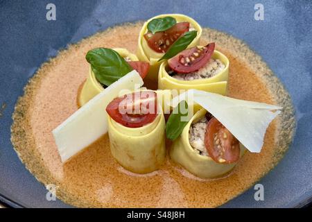 Nahaufnahme eines bunten Tellers Lasagne-Pasta auf einem Restauranttteller in Frankreich, mit Tomaten, Basilikum, Sauce und Käse in Scheiben Stockfoto