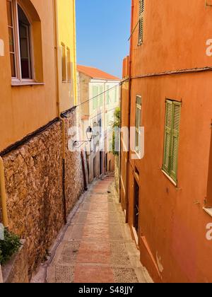 Romantische Postkarte mit gelben und orangefarbenen französischen Apartments entlang einer engen Gasse in Menton, cote d'Azure, Frankreich Stockfoto