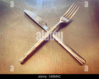 Silbernes Messer und Gabel auf einem Silberteller auf einer Küchenplatte aus Metall-Stahl in einem Restaurant, bereit für den Gebrauch, da sie super sauber glänzend glänzend zum Essen sind Stockfoto