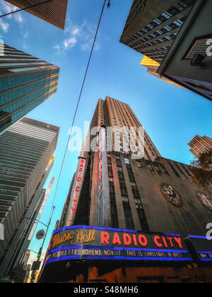 Blick auf das Gebäude der Radio City Music Hall und die umliegenden Wolkenkratzer vor dem leuchtend blauen Himmel Stockfoto