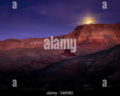 Ein Vollmond erhebt sich über den Bergen in der Virgin River Gorge bei Cedar Pocket in der Nähe von Littlefield, Arizona Stockfoto