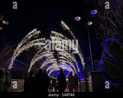 Eine Winterszene, in der die Menschen zu Weihnachten unter einem Bogen aus Lichtern im Freizeitpark Liseberg, Göteborg, Schweden, spazieren. Stockfoto