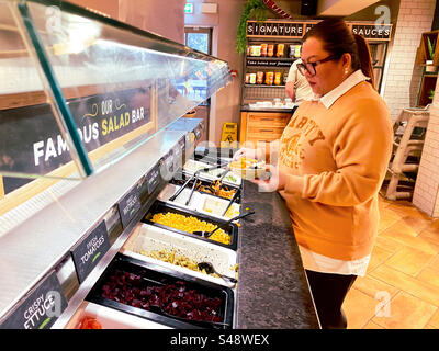 Eine Dame von hilft sich bei einem Selbstbedienungsbuffet-Salat in einem Harvester-Restaurant. Stockfoto