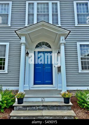 Blaue Tür auf grauem Haus in Guilford, Connecticut, USA. Vintage-Architektur. Eingang mit Schiefertreppen und Blumentöpfen. Stockfoto