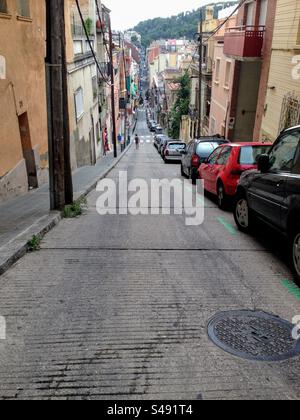 Schmale, abschüssige Stadtstraße mit geparkten Autos auf einer Seite in der Altstadt von Barcelona, Katalonien, Spanien Stockfoto